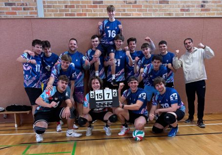 Unsere 1. Herren Gruppenselfie einer Volleyballmannschaft mit Pokal, jubelnde Spieler in blauen Trikots.